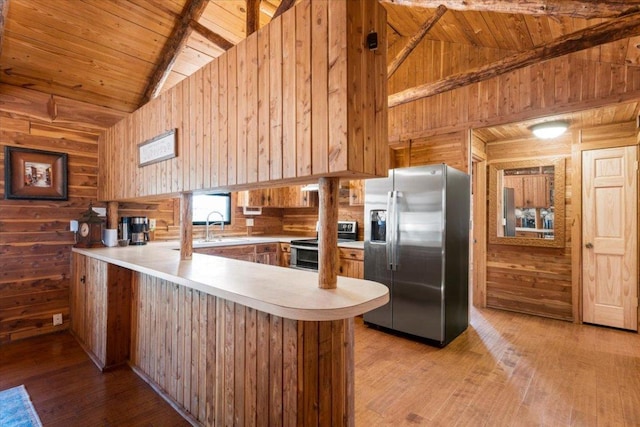 kitchen with stainless steel appliances, wooden ceiling, a peninsula, and wooden walls