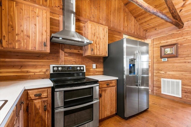 116 Yucca Ln, Bastrop, TX 78602 - kitchen featuring appliances with stainless steel finishes, wall chimney range hood, wooden ceiling, wooden walls, and light wood-style floors