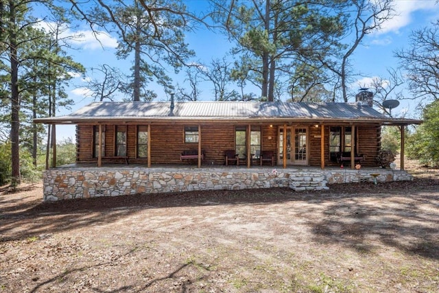 back of house with metal roof, a porch, and log siding