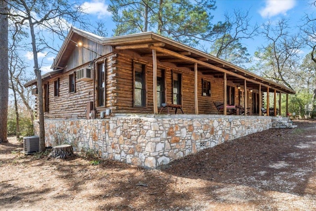 view of side of home with a porch, log exterior, and central AC unit