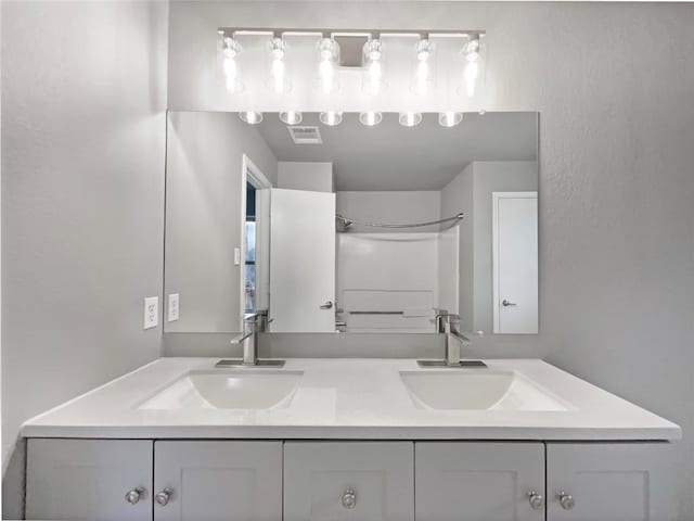 bathroom with double vanity, a sink, and visible vents