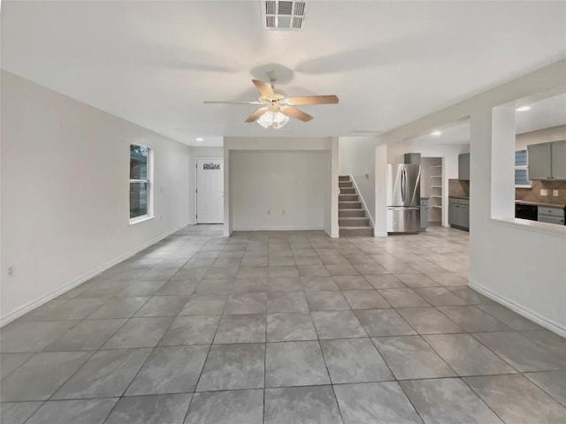 unfurnished living room featuring visible vents, baseboards, and stairs