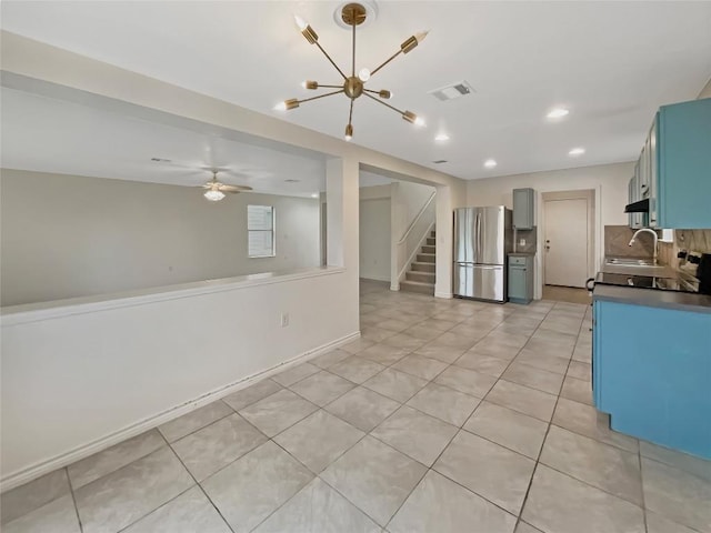 kitchen featuring blue cabinetry, dark countertops, visible vents, decorative backsplash, and freestanding refrigerator