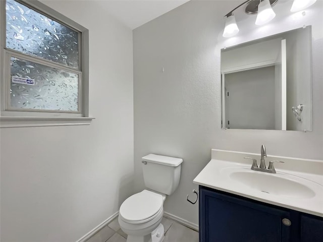 bathroom with toilet, tile patterned flooring, vanity, and baseboards