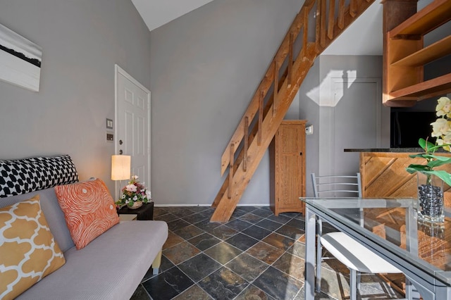 interior space with lofted ceiling, stone tile floors, stairway, and baseboards