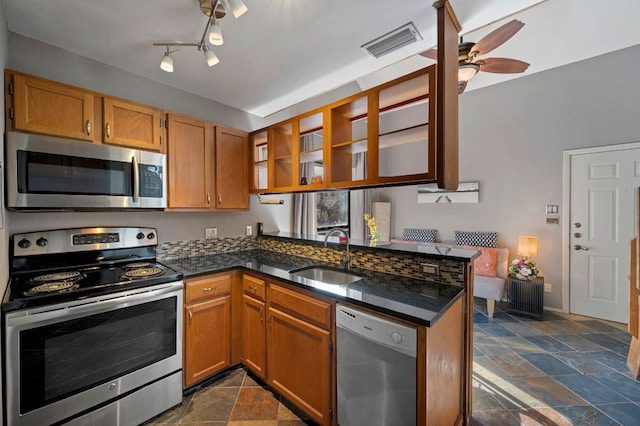 kitchen with stone tile floors, a sink, visible vents, appliances with stainless steel finishes, and glass insert cabinets