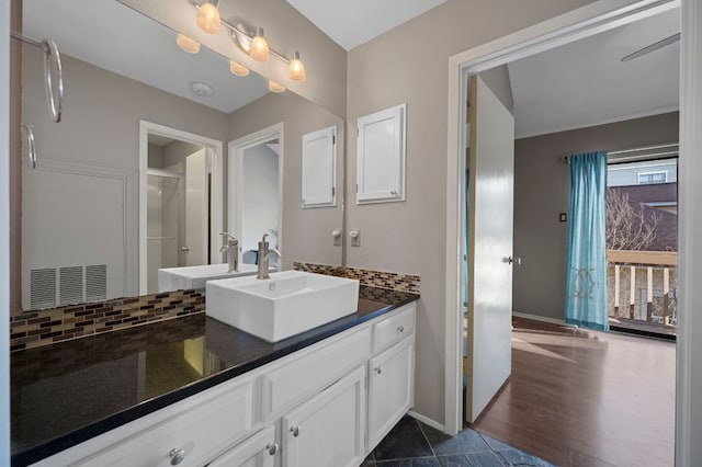 bathroom featuring tile patterned flooring, a shower with shower door, vanity, baseboards, and decorative backsplash