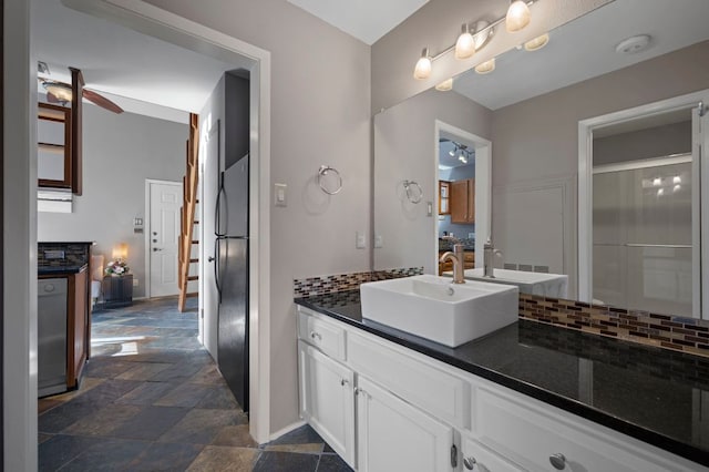 bathroom featuring baseboards, ceiling fan, stone finish floor, vanity, and backsplash