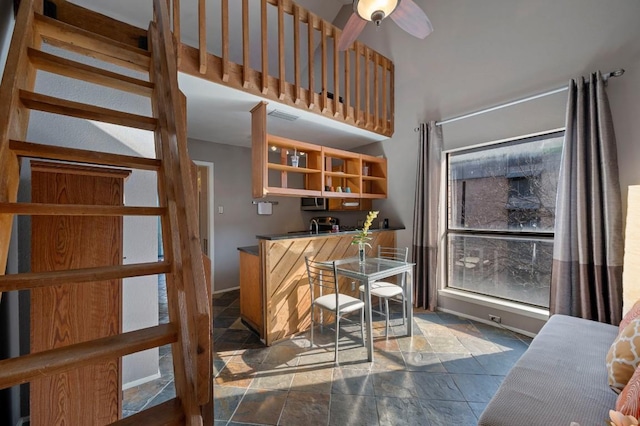 bar featuring stainless steel microwave, visible vents, a high ceiling, stone finish flooring, and ceiling fan