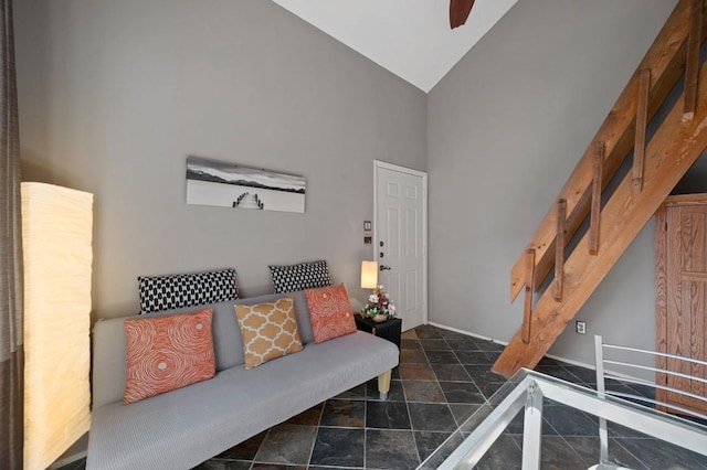 living room with high vaulted ceiling, stone finish flooring, and stairs