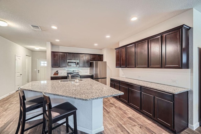 112 Quarton Dr, Hutto, TX 78634 - kitchen featuring appliances with stainless steel finishes, light wood-type flooring, tasteful backsplash, recessed lighting, and a textured ceiling