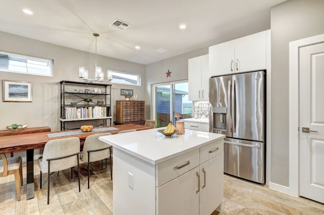 kitchen featuring a center island, stainless steel fridge, plenty of natural light, and visible vents