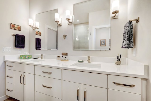 full bath with double vanity, tiled shower, and a sink