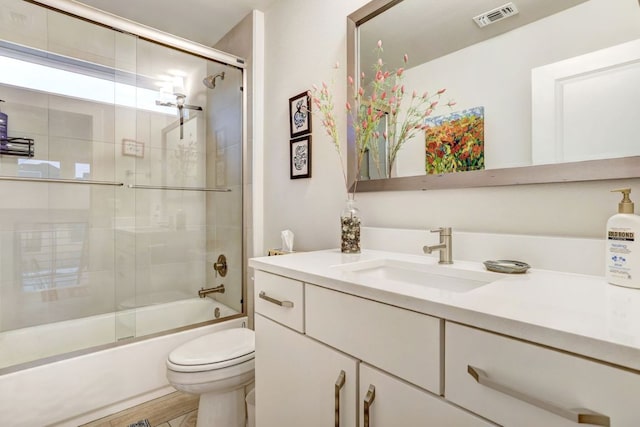 full bathroom featuring toilet, bath / shower combo with glass door, vanity, and visible vents