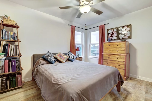 bedroom with wood finished floors, a ceiling fan, and baseboards