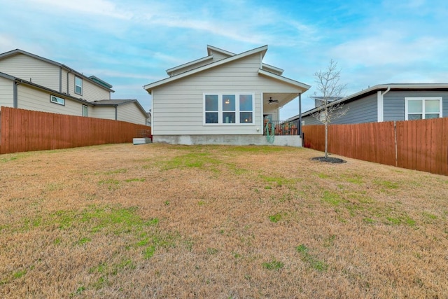 back of property featuring ceiling fan, a yard, and a fenced backyard