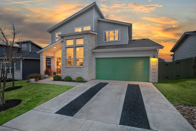 modern home with an attached garage, a shingled roof, fence, a yard, and concrete driveway