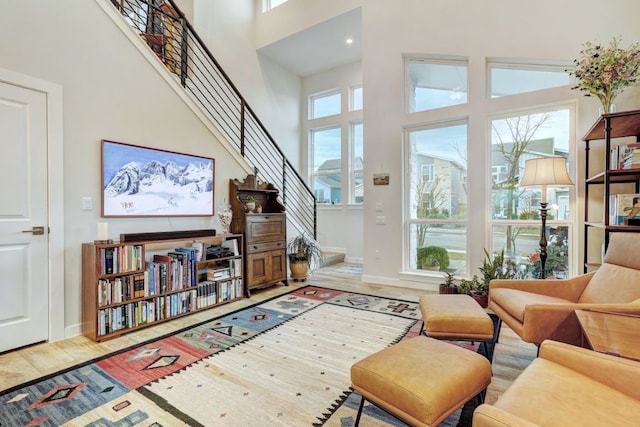 interior space featuring stairs, plenty of natural light, a towering ceiling, and wood finished floors