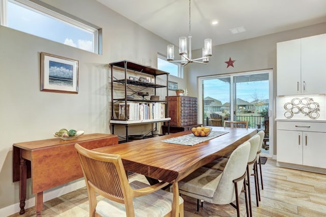 dining space with visible vents, light wood finished floors, a wealth of natural light, and a notable chandelier