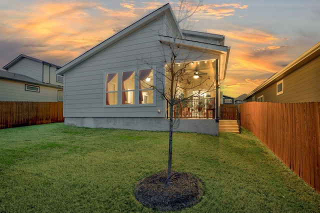 property exterior at dusk with a lawn and a fenced backyard