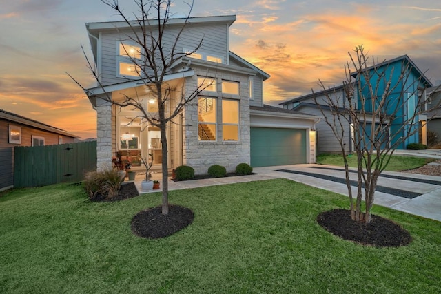 contemporary house with driveway, stone siding, fence, and a front yard