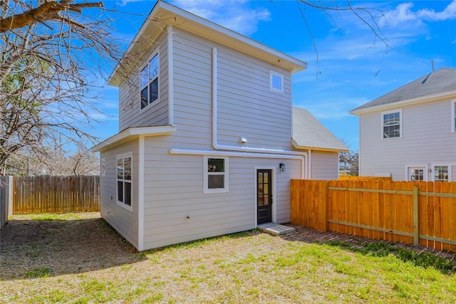 rear view of house featuring a fenced backyard and a lawn