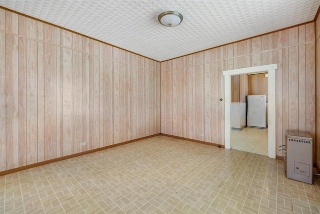 spare room with brick patterned floor, heating unit, wooden walls, and baseboards