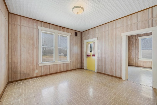 unfurnished room featuring brick patterned floor, wood walls, and baseboards
