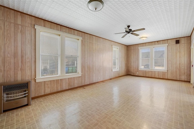 empty room with wooden walls, heating unit, and baseboards
