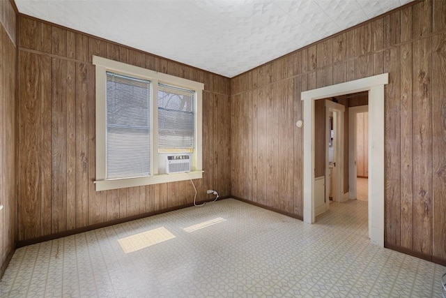 unfurnished room featuring wooden walls, baseboards, and tile patterned floors