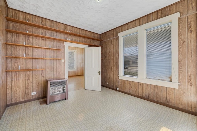 spare room featuring baseboards, wood walls, heating unit, and tile patterned floors