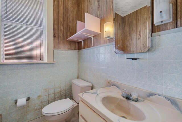 bathroom with vanity, toilet, and tile walls