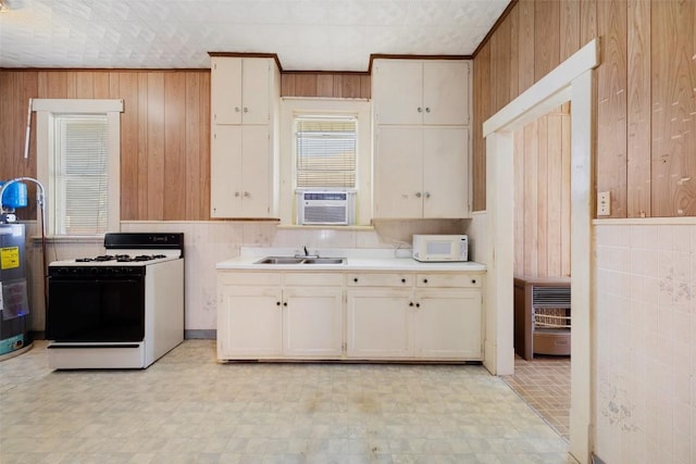 kitchen featuring light floors, light countertops, a sink, wood walls, and white appliances