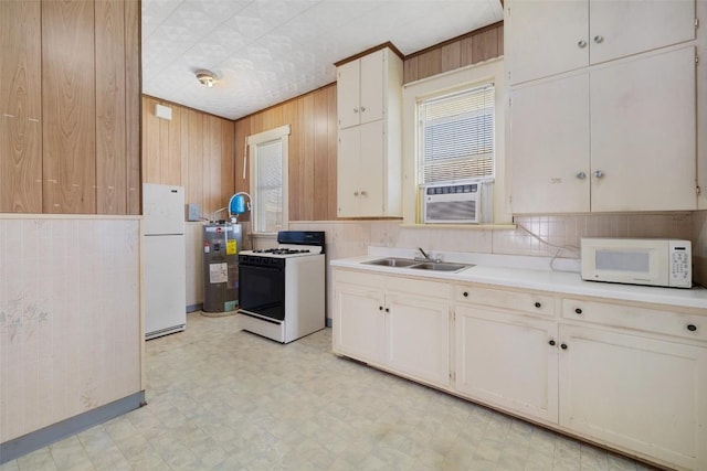 kitchen featuring light floors, white appliances, a sink, and wooden walls