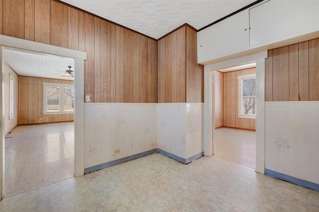 spare room with wooden walls, a ceiling fan, and tile patterned floors