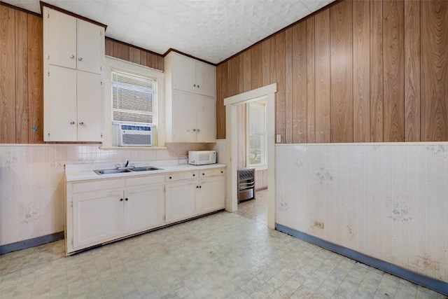 kitchen with white microwave, a sink, white cabinets, light countertops, and light floors
