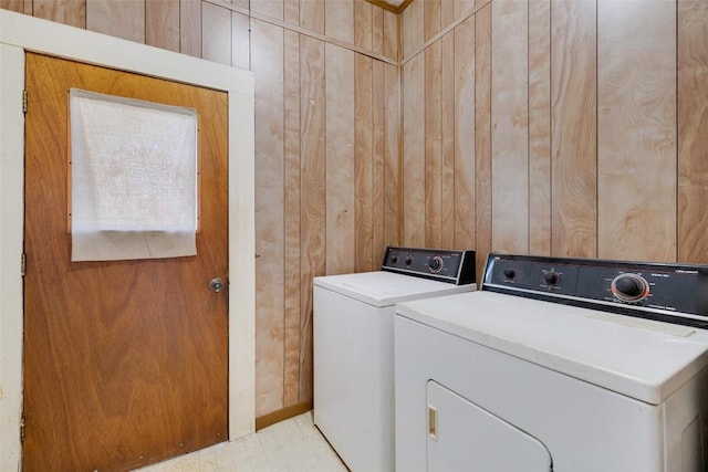 clothes washing area featuring laundry area, tile patterned floors, washer and dryer, and wood walls