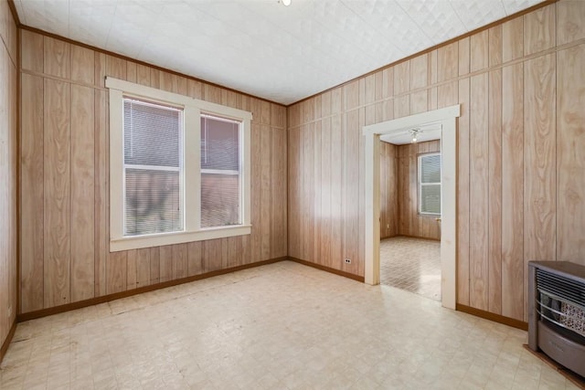 empty room featuring heating unit, light floors, wooden walls, and ornamental molding