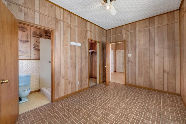 unfurnished room with wooden walls, baseboards, and brick patterned floor