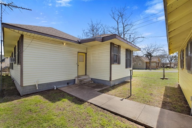 view of front of house featuring entry steps, a shingled roof, a front lawn, and cooling unit