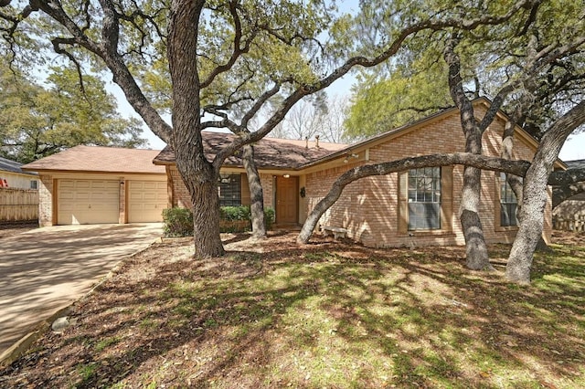 single story home featuring concrete driveway, brick siding, fence, and an attached garage