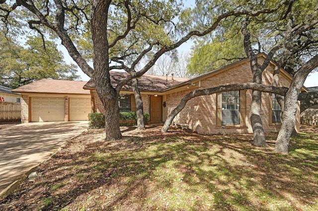 ranch-style home featuring brick siding, driveway, fence, and an attached garage