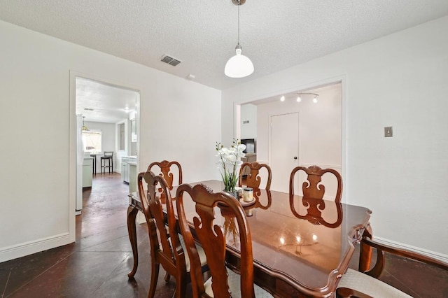 dining space featuring concrete floors, visible vents, a textured ceiling, and baseboards