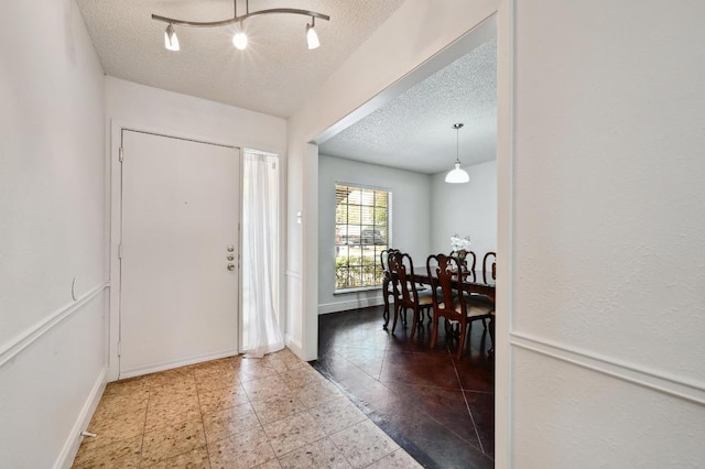 foyer featuring baseboards and a textured ceiling