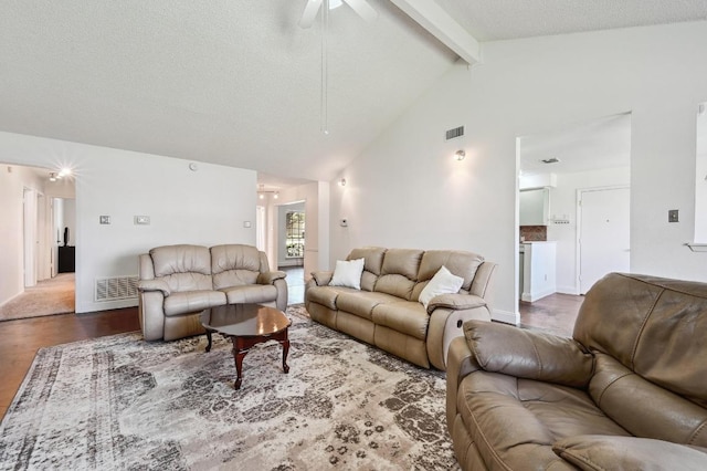 living room featuring visible vents, beamed ceiling, a textured ceiling, and wood finished floors