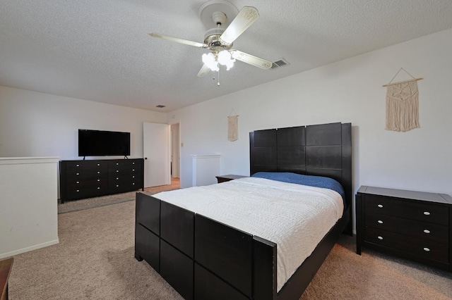 bedroom with a textured ceiling, light carpet, visible vents, and a ceiling fan