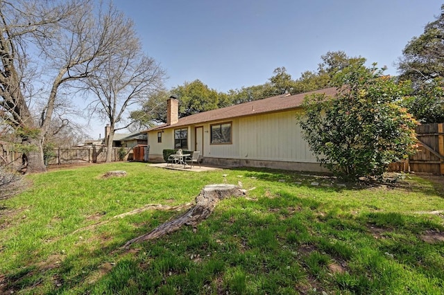 back of property with a yard, a patio, a chimney, and a fenced backyard