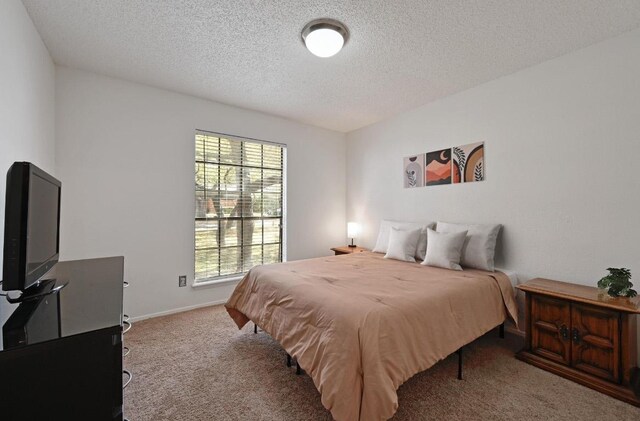 carpeted bedroom featuring a textured ceiling and baseboards