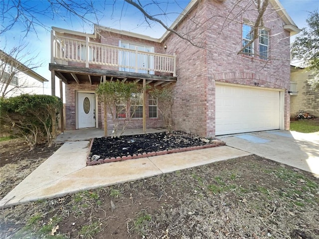 view of front of home with a garage, a balcony, driveway, and brick siding