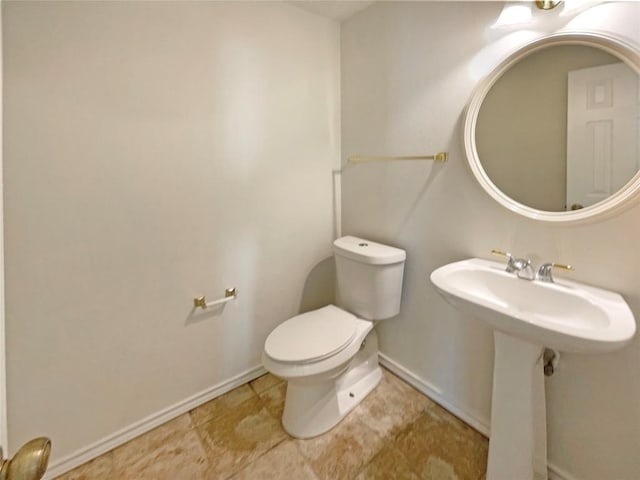 half bathroom with a sink, toilet, and baseboards